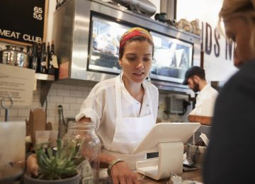 Young woman serving a customer at small shop - minimum wage