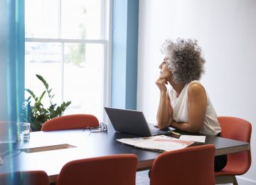 Image of woman looking of window in boardroom and reviewing NOL rules