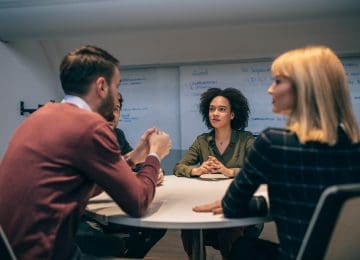 Image of people sitting around table and discussing sale agreement of business