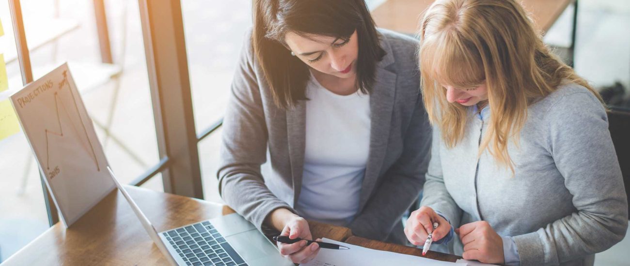 Two women reviewing qualified opportunity zone investments