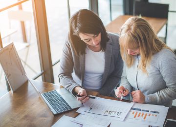 Two women reviewing qualified opportunity zone investments