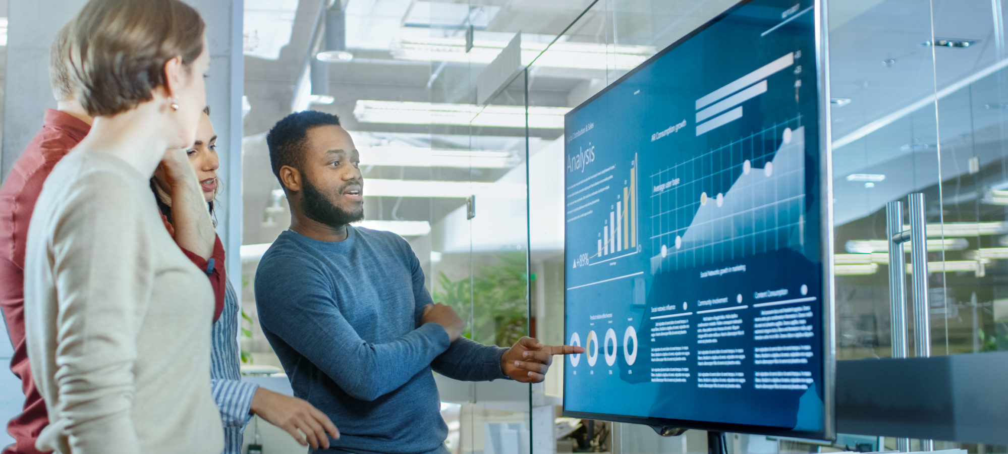 Four coworkers looking at company's real-time financial data on digital screen