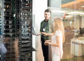 Two business people standing in server room evaluating cloud vs. on-premise solutions